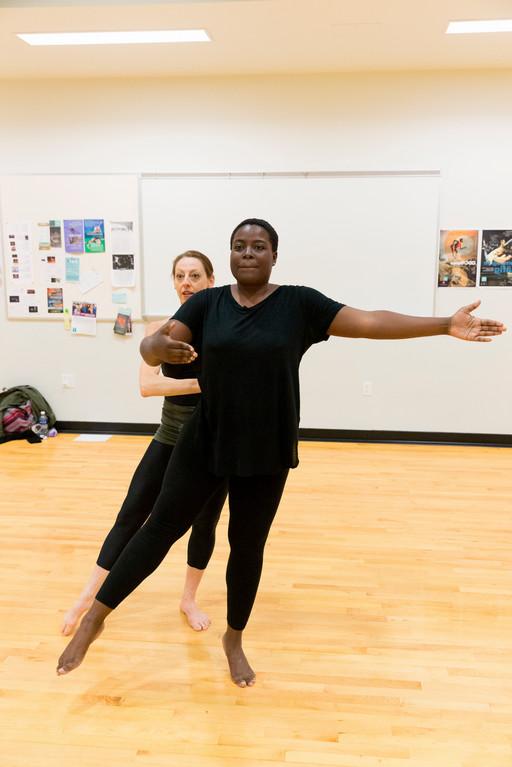 dance student standing in tendu position with teacher behind